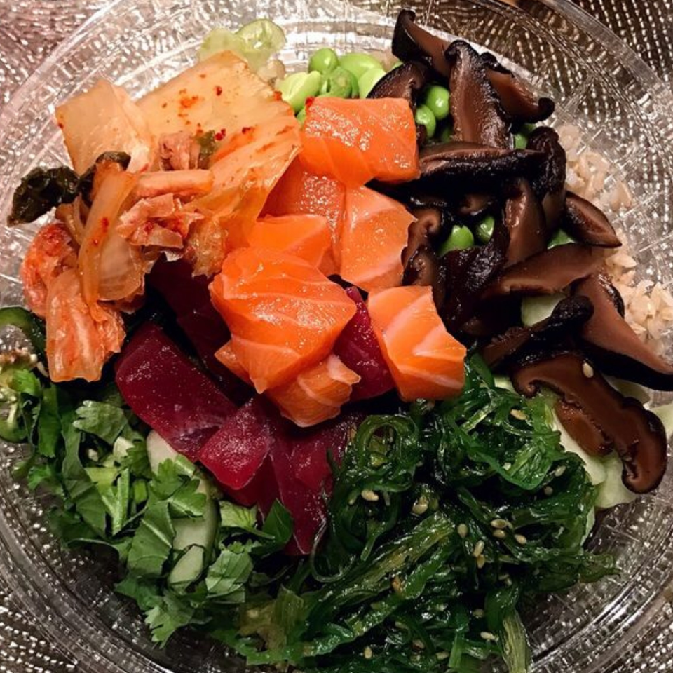 A vibrant Poke Ice bowl filled with salmon, kimchi, seaweed, mushrooms, edamame, and greens.