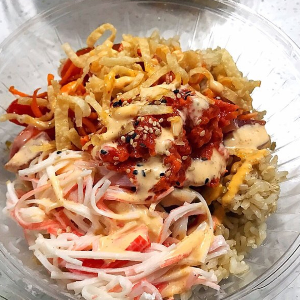 A Poke Ice poke bowl with crab salad, spicy tuna, crispy wontons, and brown rice.