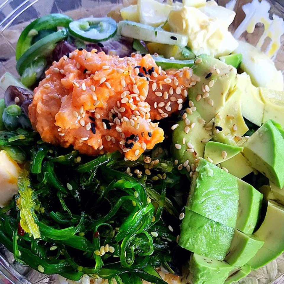 Close-up of a Poke Ice bowl with salmon, avocado, seaweed, and sesame seeds.